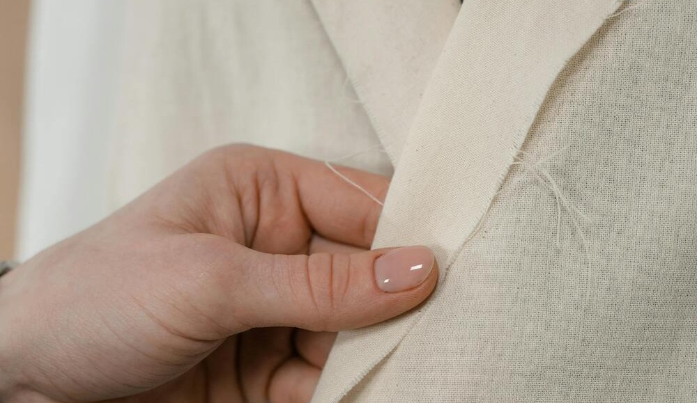 A hand checking the edge of unbleached cloth